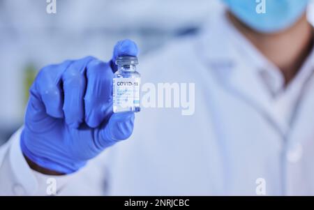 La cura per il covid è qui. uno scienziato irriconoscibile che tiene in mano una bottiglia del vaccino covid 19. Foto Stock