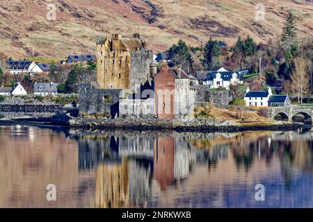 Eilean Donan Castello Loch Duich Scozia il castello si riflette nel lago di mare e circondato da case del villaggio di Dornie Foto Stock