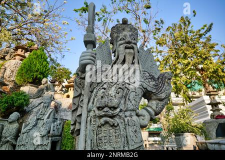 Statua in pietra di una storica figura cinese portata dalla Cina come zavorra sulle navi che consegnano riso, in un giardino a Wat Suthat, Bangkok, Thailandia Foto Stock