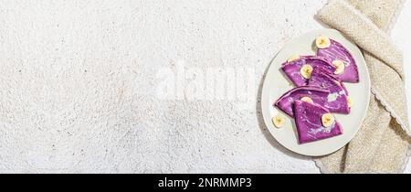 Frittelle di lavanda sottili con fette di banana e condimento dolce. Vegan sano non lattosio e senza glutine cibo, concetto di colazione. Luce dura alla moda, dar Foto Stock