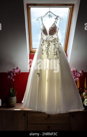 armadio della sposa e dello sposo e articoli di abbigliamento abito da sposa matrimonio appeso sullo sfondo del lucernario Foto Stock