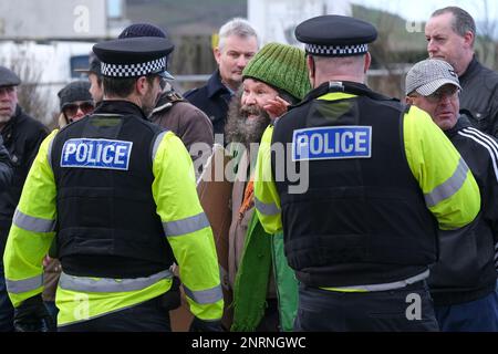 Gli ufficiali di polizia si confrontano con un protesista arrabbiato che urla durante una manifestazione organizzata dal gruppo di destra Reform UK contro i richiedenti asilo pla Foto Stock