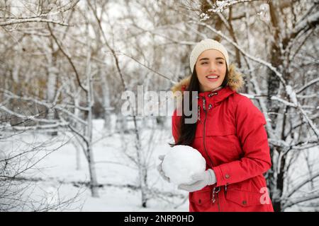 Giovane donna che tiene la palla di neve all'aperto il giorno d'inverno. Spazio per il testo Foto Stock