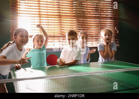 Bambini felici e carini che giocano a ping pong al coperto Foto Stock