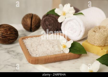 Composizione con bellissimi fiori di gelsomino e sale marino su tavola di marmo bianco Foto Stock