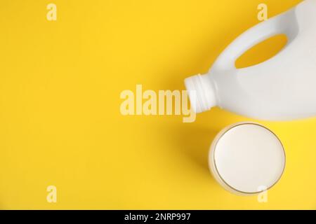 Gallone bottiglia e bicchiere di latte su sfondo giallo, piatto. Spazio per il testo Foto Stock