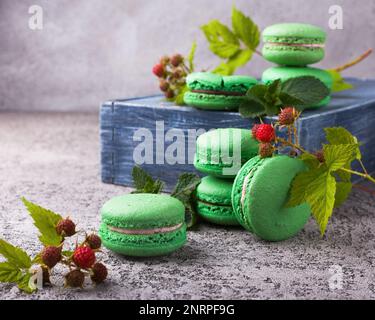 Macaron francesi alla menta verde fresco su scatola di legno e tavolo in cemento grigio chiaro. Primo piano, copia spazio, messa a fuoco selettiva. Sfondo orizzontale. Foto Stock