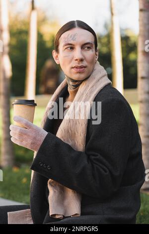 uomo elegante in cappotto e sciarpa che tiene la tazza di carta con il caffè per andare, immagine di scorta Foto Stock