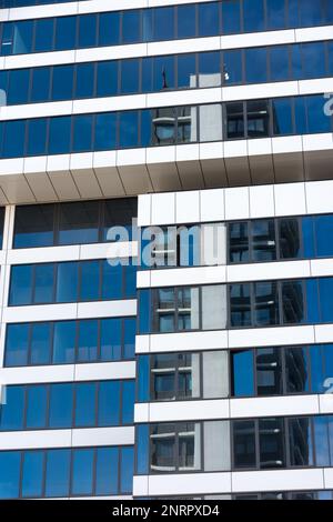 Moderna facciata in vetro con un cielo blu che riflette nelle finestre Foto Stock