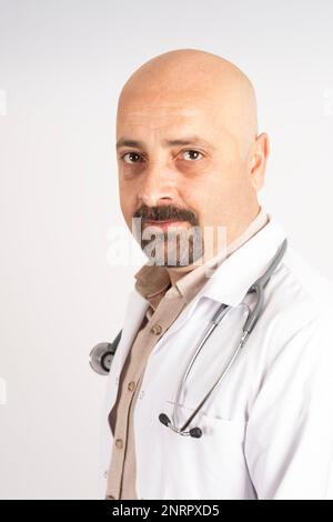 Ritratto di bel medico, calvo caucasico e ritratto di bel medico. Uniforme bianca con stetoscopio. Grigio chiaro isolato. Foto Stock