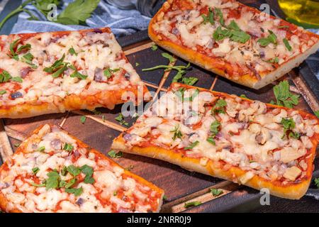 Pizza baguette fatta in casa. Baguette barche. Sandwich di casseruola al forno con pancetta, funghi, pomodori, mozzarella di pollo Foto Stock