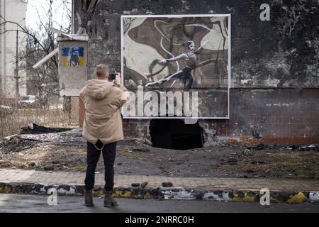 Irpin, Ucraina. 25th Feb, 2023. Irpin, Ucraina - 25 febbraio 2023: Opere d'arte del famoso graffiti Banksy al muro di un edificio distrutto nel villaggio ucraino di Irpin, che è stato pesantemente danneggiato dai combattimenti nei primi giorni dell'invasione russa. (Foto di Kish Kim/Sipa USA) *** Korea out *** Credit: Sipa USA/Alamy Live News Foto Stock