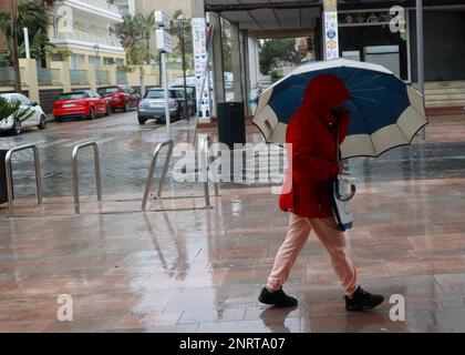 Santa Margalida, Spagna. 27th Feb, 2023. Una donna cammina con un ombrello nel bel tempo a Can Picafort. Piogge con basse temperature sono previste per i prossimi giorni. Credit: Clara Margais/dpa/Alamy Live News Foto Stock