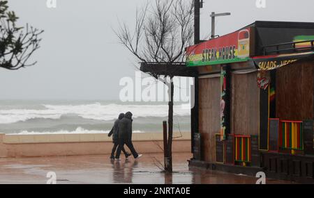 Santa Margalida, Spagna. 27th Feb, 2023. Una coppia cammina lungo il lungomare di Can Picafort in tempesta. Piogge con basse temperature sono previste per i prossimi giorni. Credit: Clara Margais/dpa/Alamy Live News Foto Stock