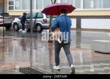 Santa Margalida, Spagna. 27th Feb, 2023. Un uomo cammina con un ombrello nel bel tempo a Can Picafort. Piogge con basse temperature sono previste per i prossimi giorni. Credit: Clara Margais/dpa/Alamy Live News Foto Stock