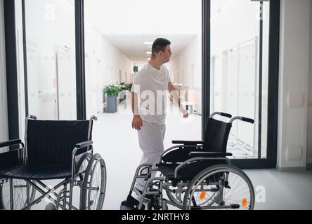 Giovane uomo con giù syndome che lavora in ospedale come caregiver. Concetto di integrazione di persone con disabilità nella società. Foto Stock