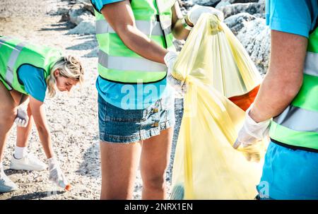 Primo piano di volontari organizzati che indossano uniformi in spiaggia attività di pulizia dalla spazzatura rifiuti - concetto di conservazione ambientale per la plastica ma Foto Stock