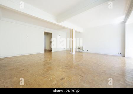 Soggiorno di una casa vuota con pavimenti in parquet disposti a scacchiera con colonna dipinta e accesso senza porta Foto Stock