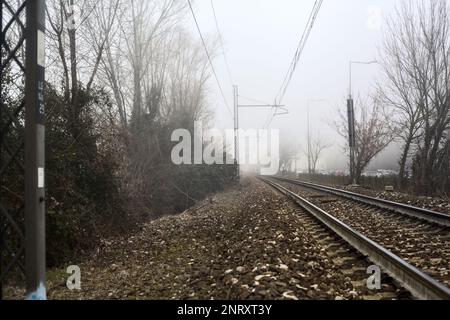 Ferrovia che passa in un parco in una giornata di nebbia Foto Stock