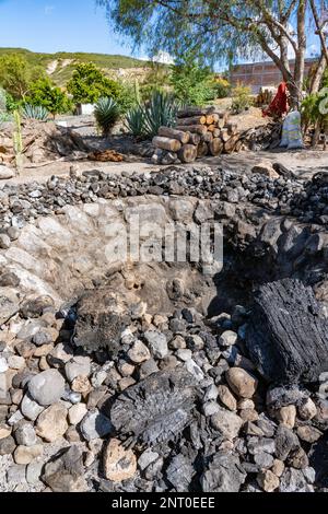 Una fossa o un forno per tostare i cuori di agave in una piccola distilleria di mezcal a Santiago Matatlan, Oaxaca, Messico. Queste piccole imprese a conduzione familiare ma Foto Stock