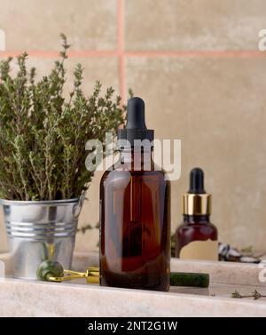 Olio essenziale di timo in bottiglia di vetro con contagocce e rametti di timo fresco sulla tavola, ingrediente cosmetico Foto Stock