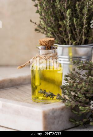 Olio essenziale di timo e rametti di timo fresco su tavola, ingrediente per cosmetici e cucina Foto Stock