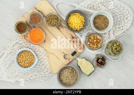 Vari alimenti biologici in vasetti di vetro e ciotole su uno sfondo di legno bianco. Shopping e stoccaggio prodotti agricoli. Vista dall'alto. Spazio di copia. Foto Stock