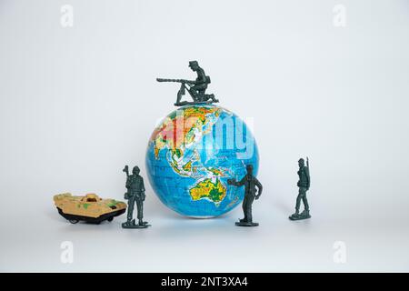 Globo in ucraino e soldati di plastica e giocattoli di carri armati per bambini su uno sfondo bianco primo piano, esercito Foto Stock