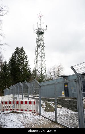 Edificio industriale con recinzione e radar Torre con diversi dispositivi di misurazione e sensori, vista ad angolo basso durante le giornate nuvolose, ripresa verticale Foto Stock