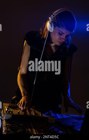 DJ femminile che suona musica su un mixer. Luce blu parassita visibile Foto Stock