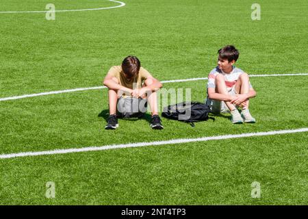 Ragazzo adolescente confortante consolante infastuito triste amico nello stadio della scuola. Educazione, bullismo, conflitto, relazioni sociali, problemi a scuola, apprendimento Foto Stock