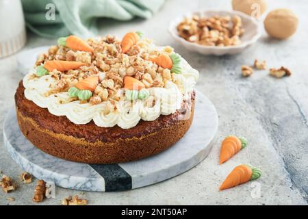 Torta di carota di Pasqua con gelato al formaggio cremoso. Deliziosa torta di carote con noci e crema di formaggio glassa sul tavolo grigio di fondo in cemento per festi Foto Stock