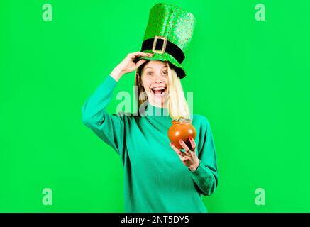 Giorno di San Patrizio. Donna sorpresa in cappello Leprechaun con pentola d'oro. Tradizione del giorno di San Patrizio. Ragazza stupita con pentola di soldi per Patricks Day Foto Stock