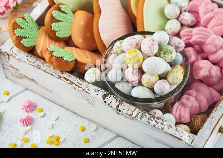 Concetto di Pasqua dolce. Dolce Pasqua bambini assortimento vacanze marshmallows coniglio, cioccolatini uova di pasqua, caramelle, coniglietto, snack su sfondo di legno bianco Foto Stock