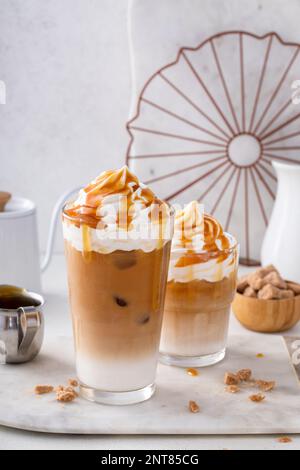 Latte di caramello ghiacciato in un bicchiere alto con gocce di salsa di caramello, bevanda di caffè fantasia Foto Stock