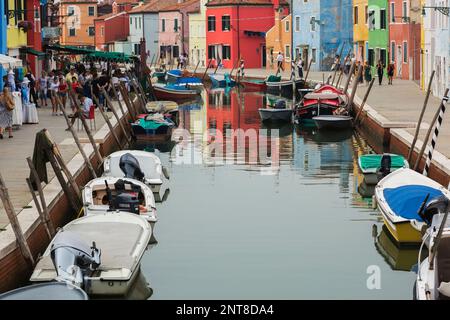 Barche ormeggiate sul canale fiancheggiato da case di stucco colorate, negozi e turisti, Isola di Burano, Laguna di Venezia, Venezia, Veneto, Italia. Foto Stock