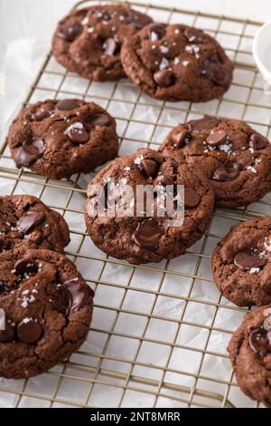 Biscotti al doppio cioccolato con gocce di cioccolato e sale scaglie su una griglia di raffreddamento Foto Stock