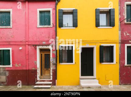 Facciate in stucco rosa e giallo con gradini e persiane in legno verde alle finestre, Isola di Burano, Laguna di Venezia, Venezia, Veneto, Italia. Foto Stock