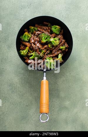 Manzo e broccoli in un piccolo wok vista dall'alto su sfondo verde Foto Stock