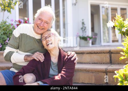 Ritratto di felice coppia anziana varia abbracciando e sorridendo in giardino Foto Stock