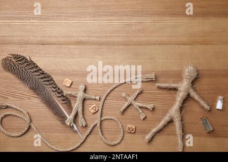 Voodoo bambola trafitto con spille e oggetti cerimoniali su tavolo di legno, piatto. Spazio per il testo Foto Stock