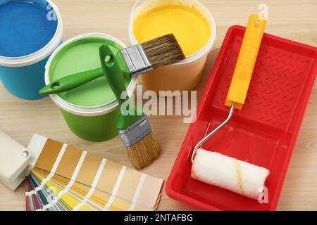 Secchi di vernici, palette e utensili decoratori su sfondo di legno chiaro, vista dall'alto Foto Stock