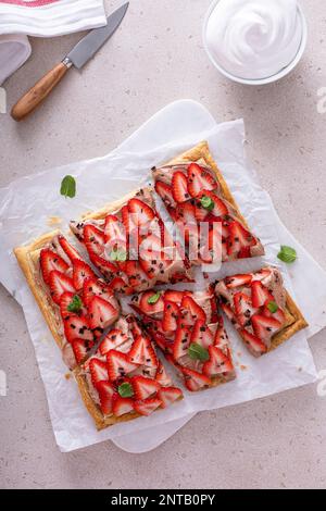 Crostata di fragole fresche e nocciole al cioccolato su pasta sfoglia tagliata a pezzi Foto Stock