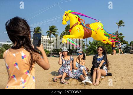 Pattaya, Thailandia. 27th Feb, 2023. I turisti posano per le foto con un aquilone alla spiaggia di Pattaya, Thailandia, 27 febbraio 2023. Gli appassionati di aquilone e i turisti si sono riuniti alla spiaggia di Pattaya per godersi il festival internazionale di aquiloni. Credit: Wang Teng/Xinhua/Alamy Live News Foto Stock