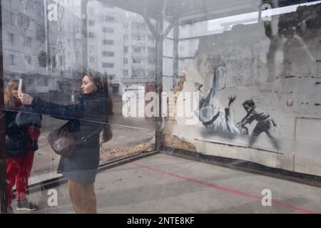 Borodyanka, Ucraina. 26th Feb, 2023. Una ragazza prende un selfie vicino al lavoro di Banksy, il lavoro dell'artista inglese Banksy è visibile su un muro distrutto, dopo che la Federazione russa ha attaccato la città di Borodyanka, le autorità hanno deciso di salvare il lavoro di Banksy e ora sono protetti dal sistema. (Foto di Maksym Polishchuk/SOPA Images/Sipa USA) Credit: Sipa USA/Alamy Live News Foto Stock