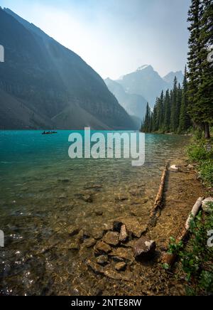 Lago Moraine con catena montuosa dai cieli nebbiosi e acque acquatiche Foto Stock