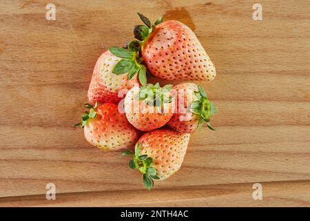 Fragole fresche selezionate, varietà di ananas impilate su fondo in legno Foto Stock