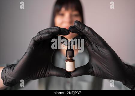 Bottiglia con pigmento per labbra o sopracciglia tatuaggio in mani di makeup master permanente femminile, selettivo focus.Bottle con inchiostro in salone senza label.Cho Foto Stock