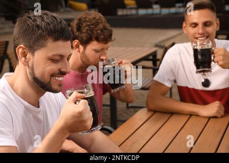 Amici con bicchieri di birra nella caffetteria all'aperto Foto Stock