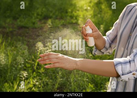 Donna che applica repellente per insetti a portata di mano in parco, primo piano. Prevenzione punture di zecca Foto Stock